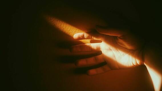 Das Bild zeigt eine Hand in einem Lichtstrahl