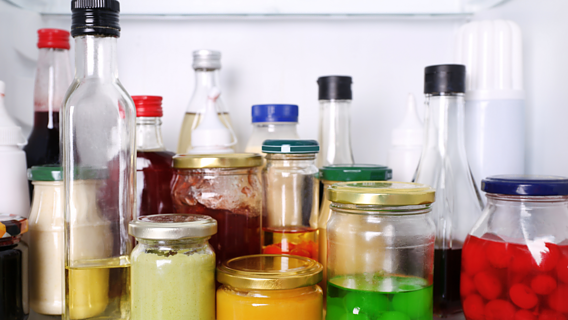 Das Bild zeigt viele verschienende Gläser und Flaschen mit Saucen und Beeren in einem Kphlschrank