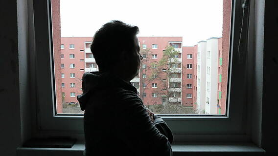 Das Bild zeigt Ben Kurpanek von hinten in seiner Wohnung am Fenster stehend.
