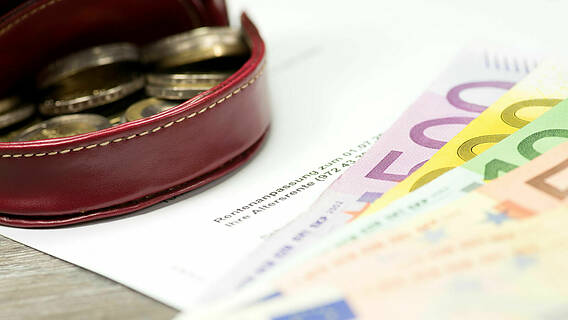 Geldscheine, eine Geldbörse mit Münzen und ein Brief, der über die Rentenanpassung informiert.