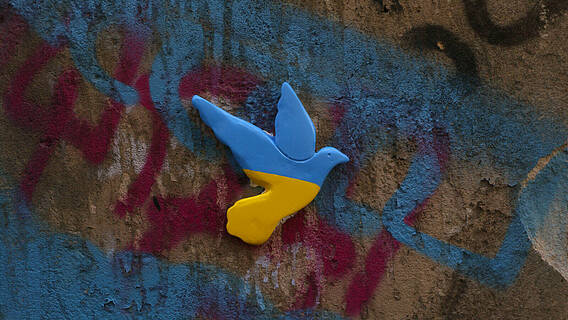 Eine Wand mit Graffiti und eine Friedenstaube in den Farben der ukrainischen Flagge