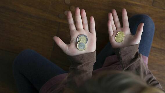Symbolfoto zum Thema Kinderarmut und Kindergrundsicherung: Kleines Mädchen zählt ihr Taschengeld, hält wenige Euromünzen in den Händen