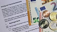 Symbolfoto: Ein Antrag auf Erwerbsminderungsrente. Darauf liegen Euro-Scheine und -Münzen.