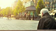 Älterer Mann sitzt auf der Bank auf einem Marktplatz