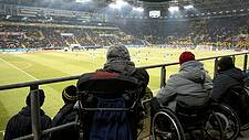 Fußballfans mit Behinderung verfolgen das Spiel von ihren Rollstuhlfahrerplätzen aus