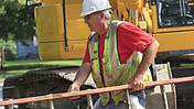 Symbolfoto: Ein älterer Bauarbeiter trägt eine Leiter