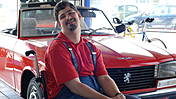 Lukas Zilch an seinem Arbeitsplatz, einem Autohaus - der Jugendlich sitzt im Rollstuhl vor einem roten Cabriolet