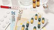 Symbolfoto: Verschiedene Arzneimittel und Euroscheine liegen auf einem Tisch