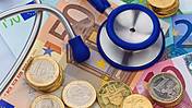 Symbolfoto: Ein Stethoskop liegt auf einem Haufen Euro-Scheine und -münzen
