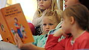 Symbolfoto: Eine Frau liest mehreren Kindern etwas vor.