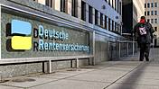 Symbolfoto: Gebäude der Deutschen Rentenversicherung, auf dem Gehweg davor geht eine Frau mithilfe eines Gehstocks.
