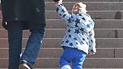 Symbolfoto: Ein Erwachsener mit einem kleinen Kind an der Hand geht eine Treppe hinauf