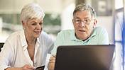 Symbolfoto: Ein älteres Paar sitzt gemeinsam vor dem Notebook, sieht sich etwas im Internet an