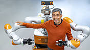 Ranga Yogeshwar mit einem humanoid gestalteten Industrie-Roboter, der ihn von hinten umarmt.