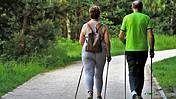 Das Foto zeigt ein älteres Pärchen beim Wandern, beide haben Nordic-Walking-Stöcke