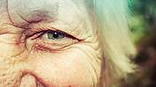 Das Bild zeigt den Ausschnitts des Gesichts einer älteren Frau. Fokus liegt auf ihrem Auge