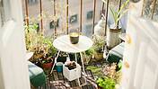 Ein kleiner Balkon mit einem Tischchen und Pflanzen