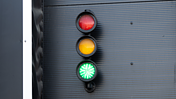 Das Bild zeigt eine Ampel, die rot, gelb und grün anzeigt auf grauem Hintergrund.