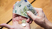 Hände einer älteren Person halten Euroscheine und Mpnzen im Wert von 10,45 Euro