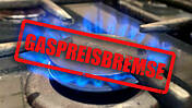 Gasherd im Privathaushalt mit brennender Flamme, darüber ist ein Stempel auf das Foto montiert mit der Aufschrift "Gaspreisbremse"