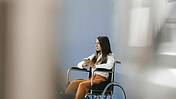 Junge Frau im Rollstuhl, sie schaut besorgt