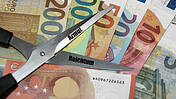 Symbolfoto: Euroscheine und eine Schere mit der Aufschrift Armut und Reichtum