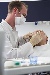 Symbolfoto: Ein Zahnarzt behandelt gerade einen älteren Patienten.