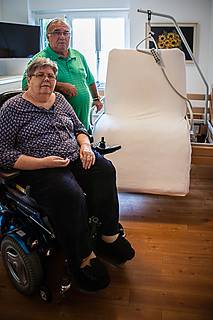 Das Foto zeigt Reiner Schweiger und seine Frau Christine, die im Rollstuhl sitzt. Im Hintergrund sieht man das Pflegebett, das der VdK für das Ehepaar durchsetzen konnte.