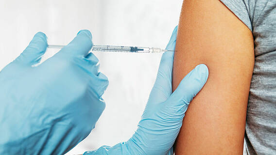 Impfung mit Spritze in Oberarm