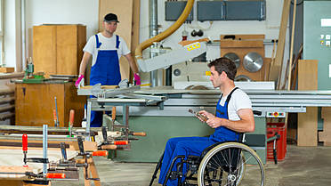 Mann im Rollstuhl arbeitet in einer Schreinerei.