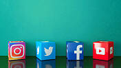 Marmor Würfel mit den Symbolen der Social Media Diensten Instagram, Twitter, Facebook und YouTube auf schwarzem Glas mit türkisfarbenen Hintergrund