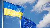 Flaggen der Ukraine und der Europäischen Union (EU) mit blauem Himmel im Hintergrund