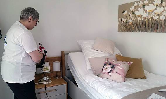 Frau bedient Fernbedienung zur Steuerung von AAL-Bett
