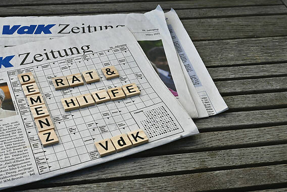 Auf dem Foto sieht man zwei VdK-Zeitungen. Auf den Zeitungen sind die Wörter Demenz, Rat und Hilfe und VdK mit Scrabble-Buchstaben gelegt.