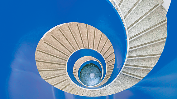 Symbolbild: Innenansicht eines sehr steilen runden Treppenhauses.
