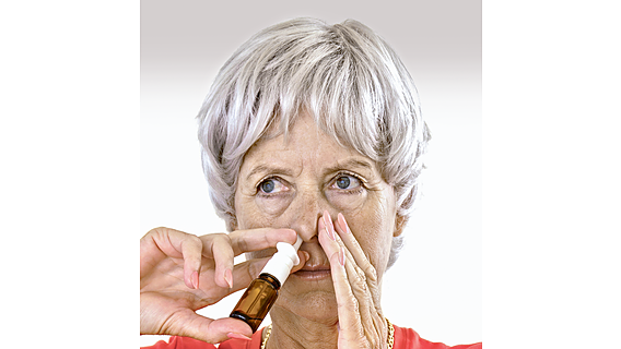 Ein Frau sprüht sich Nasenspray.