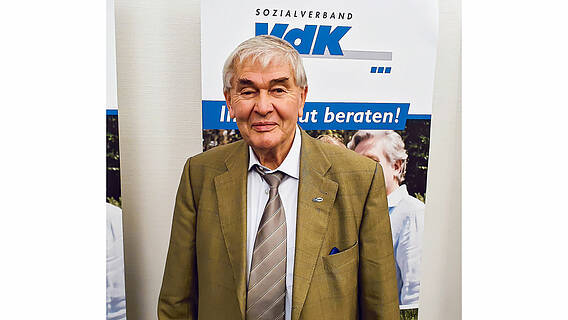 Ein Foto von Norbert Schütze. Im Hintergrund eine VdK Plakat.