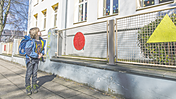 Symbolbild Ein Schulkind steht vor einem Schulgebäude.