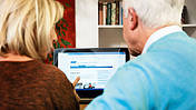 Gemütlich im Wohnzimmer klickt sich eine Frau und ein Mann durch die VdK-Internetseiten.