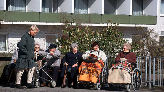 Symbolfoto: Senioren sitzen vor einem Pflegeheim