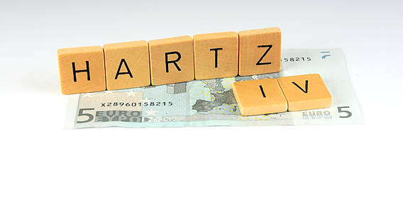 Symbolfoto: Buchstaben bilden das Wort Hartz IV, sie stehen auf einem Fünf-Euro-Schein