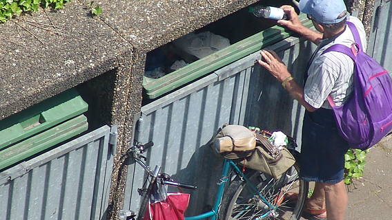 Symbolfoto: Ein Mann durchsucht einen Flaschencontainer nach Pfandflaschen
