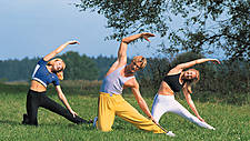 Symbolfoto: Menschen auf einer Wiese machen Yoga-Übungen