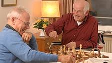 Symbolfoto: Zwei Senioren, einer davon im Rollstuhl, spielen Schach gegeneinander.