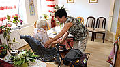 Symbolfoto: Seniorin in ihrem Zimmer mit Pflegeheim, eine Angehörige oder Pflegekraft kümmert sich um sie