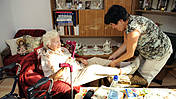 Symbolfoto: Pflegerin im Seniorenheim hilft einer alten Dame mit ihrer Gehhilfe
