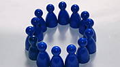 Symbolfoto: Viele blaue Spielfigürchen bilden einen Kreis