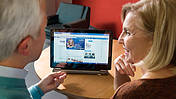 Ein Mann und eine Frau betrachten den VdK-Internetauftritt auf einem Computer