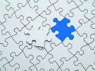 Ein blaues Puzzleteil in einem ansonsten weißen Puzzle