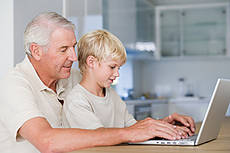 Symbolfoto: Opa und Enkel sitzen gemeinsam an einem Notebook